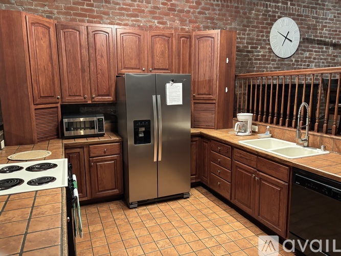 A kitchen with a stove top oven, refrigerator, and wooden cabinets.