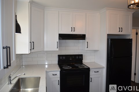 A kitchen with white cabinets and black appliances.