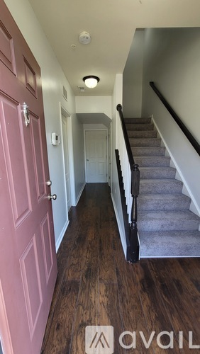 A hallway with a staircase and a pink door.