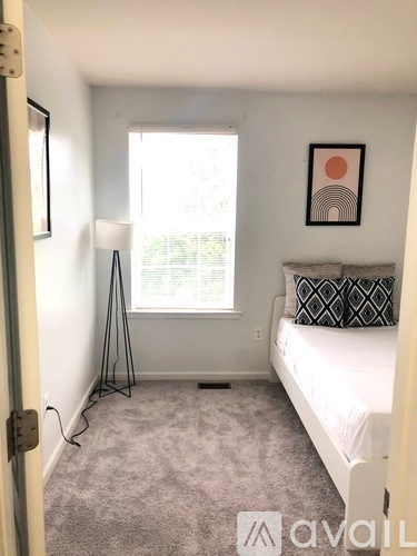 A bedroom with a bed, lamp, and window.