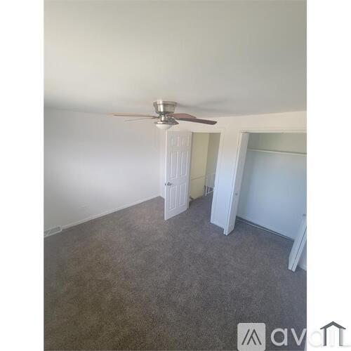 A room with a ceiling fan and carpeted floor.