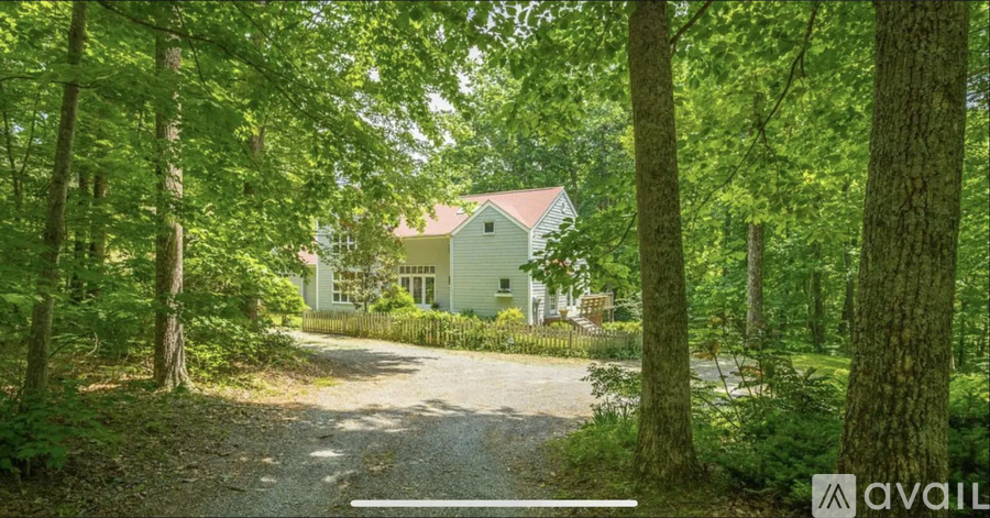 A house is surrounded by trees and is available for sale.