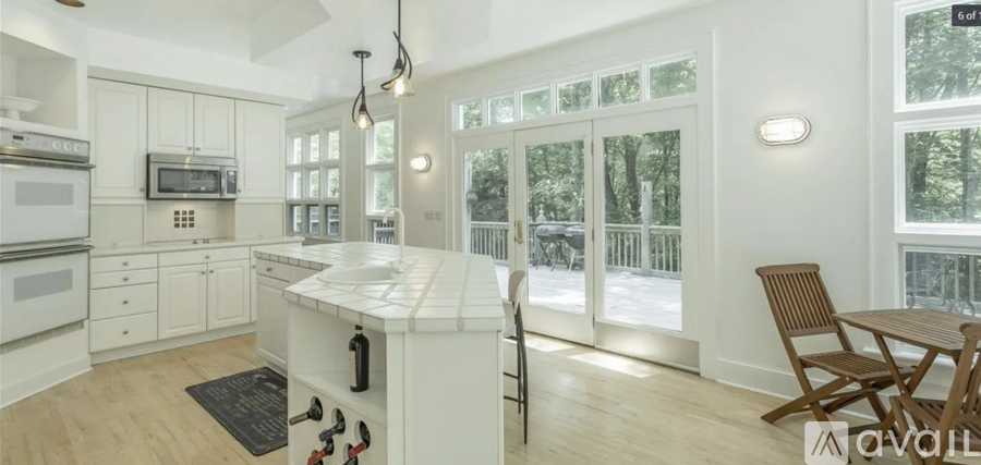 A kitchen with white cabinets and a white island with a black mat on the floor.