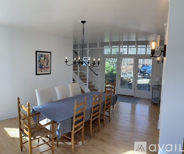 A dining room with a table set for six and a chandelier hanging from the ceiling.