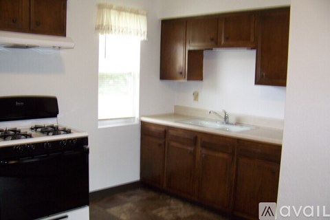 A kitchen with a black stove top oven and wooden cabinets.