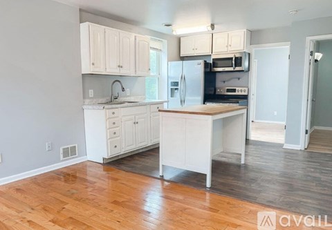 A kitchen with white cabinets and a wooden floor.
