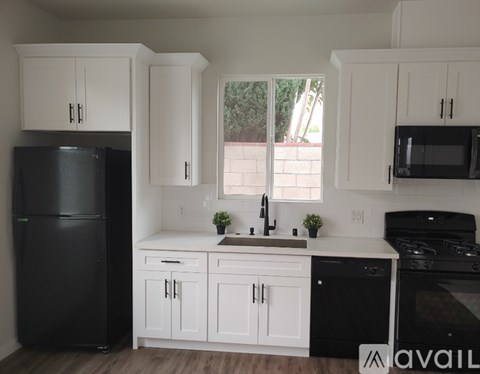 A kitchen with black appliances and white cabinets.