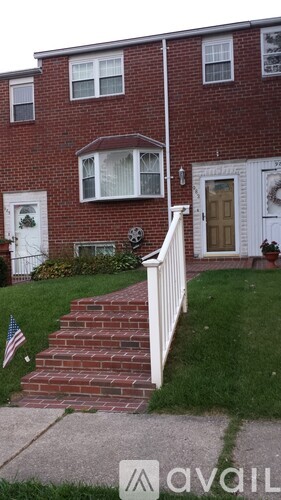 A red brick house with a white door and a small American flag on the lawn.