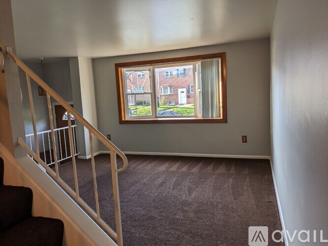 A room with a staircase leading to the upper floor and a window showing an outdoor view.