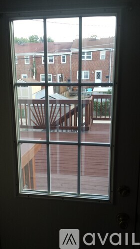 A view from a door looking out to a deck and a red brick building.