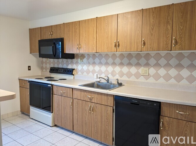 A kitchen with wooden cabinets and a black microwave above the stove.