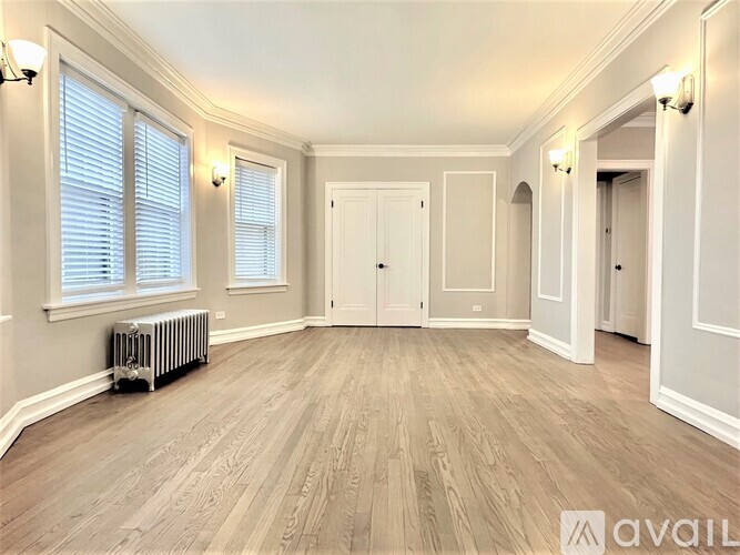 A spacious room with wooden flooring and white walls.
