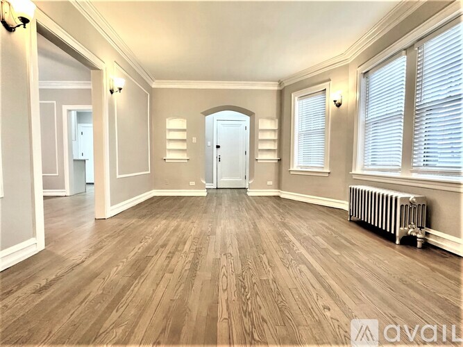 A spacious room with wooden floors and white walls.