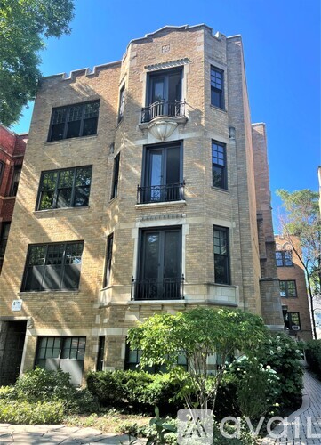 A tall building with a balcony on the second floor from the front.
