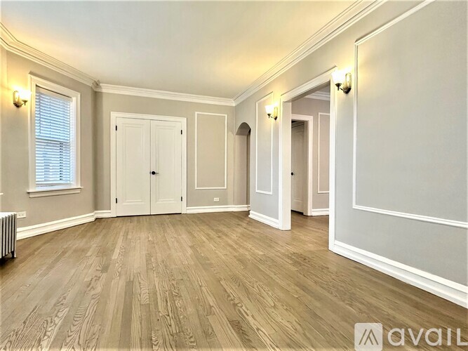 A spacious room with wooden flooring and white walls.