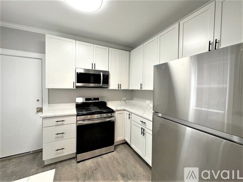 A modern kitchen with white cabinets and stainless steel appliances.