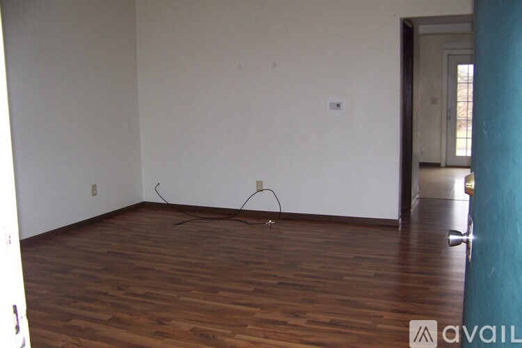 A room with wooden floors and a door on the right.