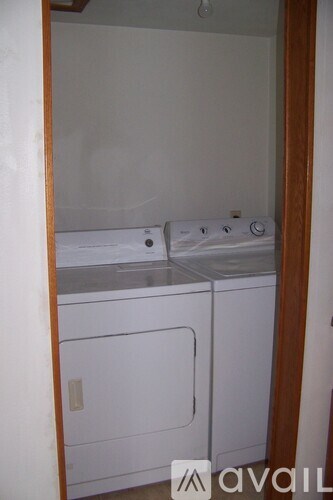 A small white washer and dryer are in a small laundry room.