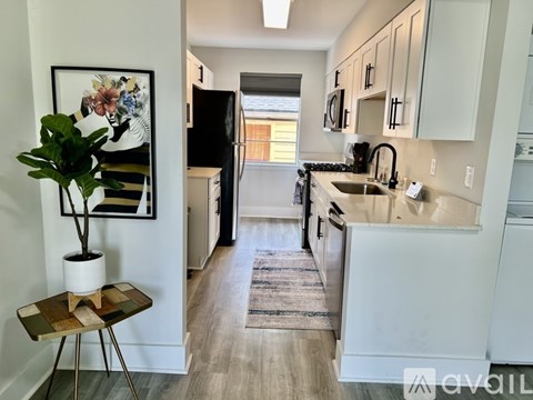 A kitchen with white cabinets and a black fridge.