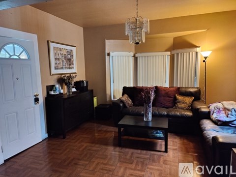 A living room with a brown leather couch and a wooden floor.