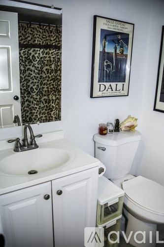 A bathroom with a toilet, sink, and a poster of Dali.