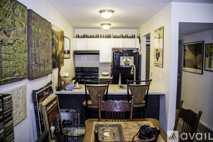 A room with a desk and chairs, a bookshelf, and a painting on the wall.