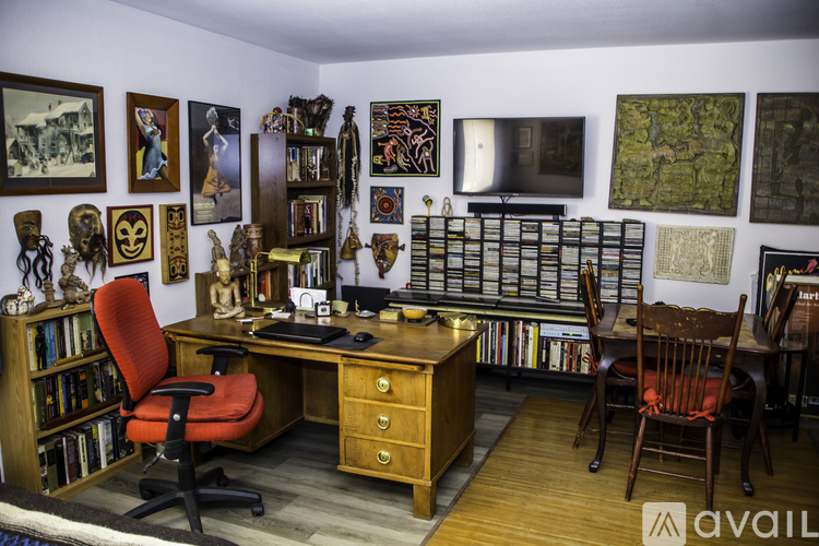 A room with a desk, chair, and bookshelf filled with various items.