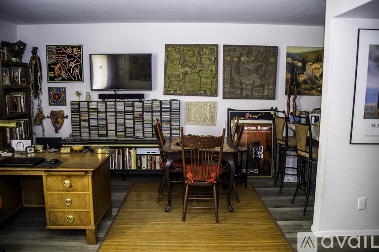 A room with a desk, chairs and pictures on the wall.