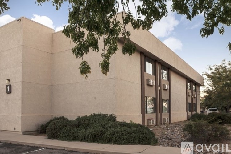 A beige building with a tree in front of it.