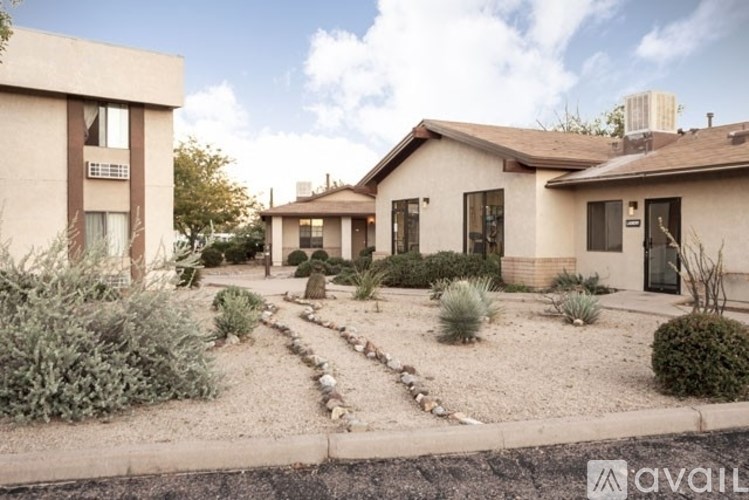 A beige house with a gravel driveway in front.