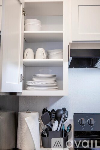A kitchen cabinet is open, revealing plates and bowls inside.
