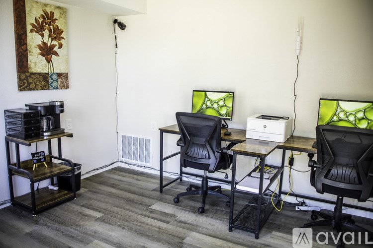 A room with a desk, chairs, and a printer.