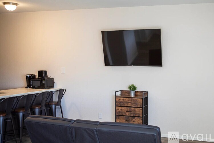 A room with a table, chairs, a television, and a plant on a wooden cabinet.