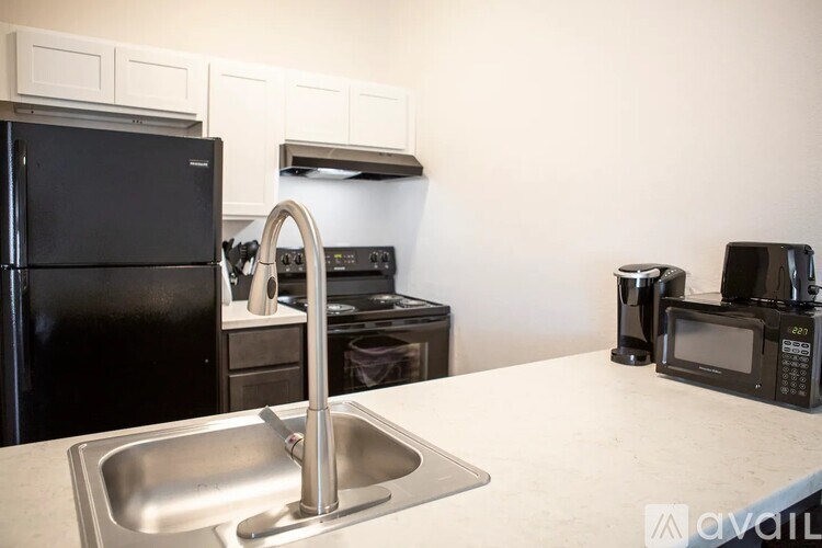 A kitchen with a black fridge, a white sink, and a black microwave.