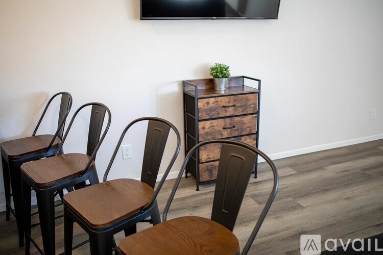 A set of four chairs with wooden seats and metal frames are arranged in a row.