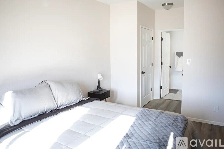 A bedroom with a bed, pillows, and a nightstand.