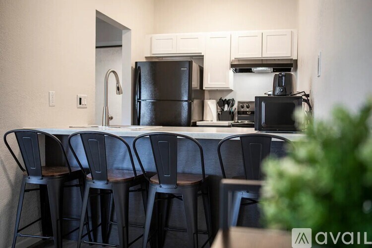 A kitchen with black appliances and a dining table with chairs.