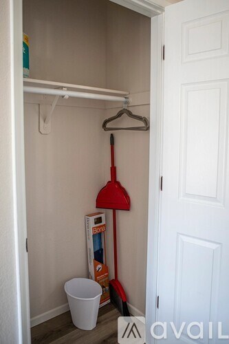 A white closet with a red broom and a white bucket.