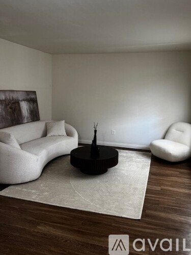 A living room with a black couch and a wooden floor.