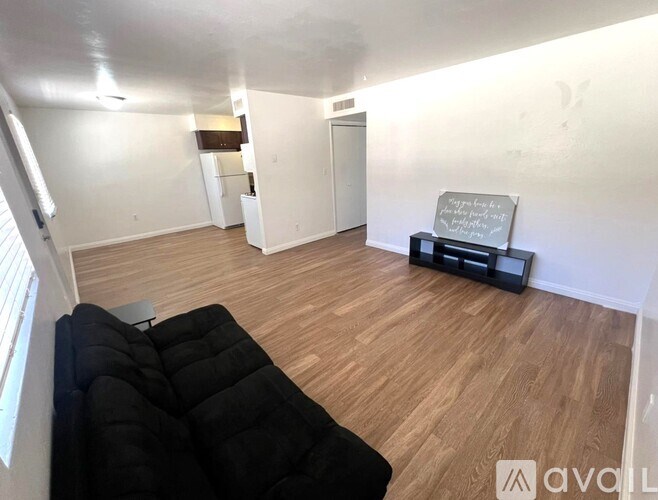 A living room with a black couch and a wooden floor.