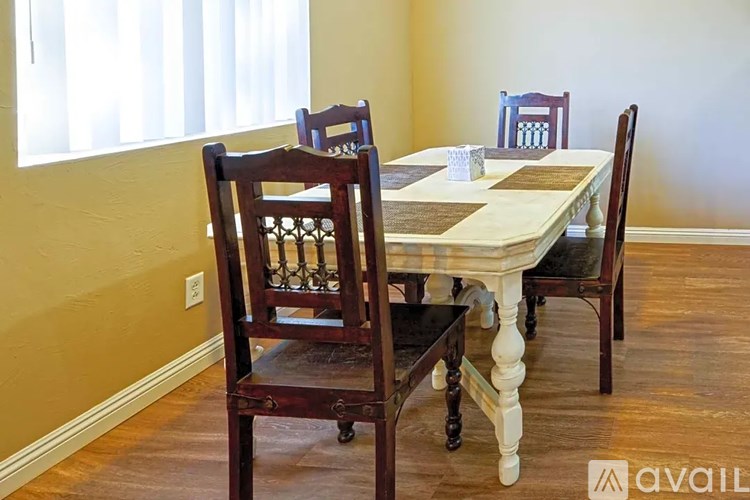 A wooden dining table with chairs and a salt shaker on it.