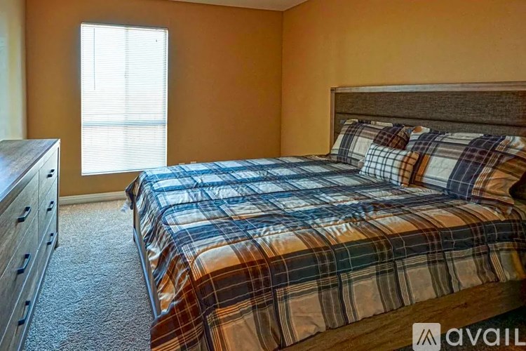 A bedroom with a bed, dresser, and window.