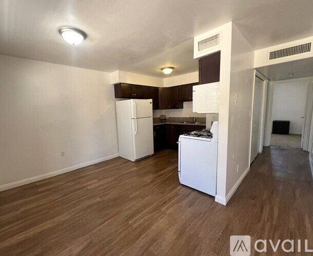 A kitchen area with a white refrigerator and wooden flooring.