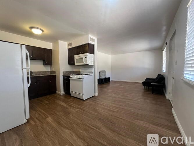 A kitchen with a white fridge, black cabinets, and a white dishwasher.