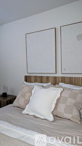 A bed with a white pillow in the middle of two other pillows.