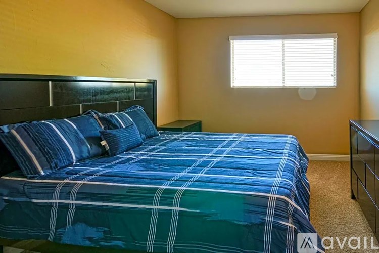 A bed with a blue and green comforter is in a room with yellow walls.