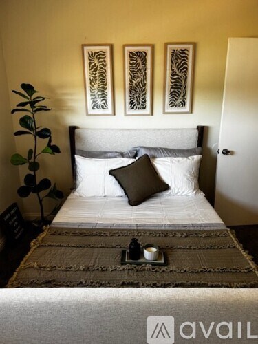 A bedroom with a bed, pillows, a tray with a candle and a plant.