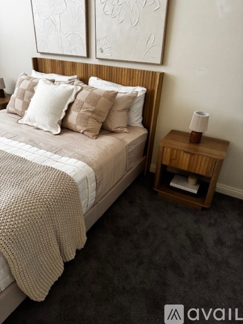 A bedroom with a bed, a nightstand, and two paintings on the wall.