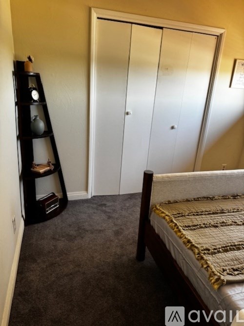 A bedroom with a bed, a wardrobe, and a shelf with a lamp on it.