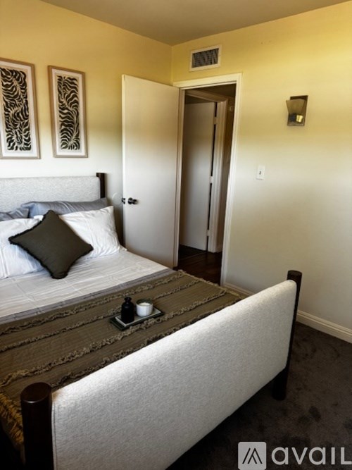 A bedroom with a bed, nightstand, and two wall hangings.